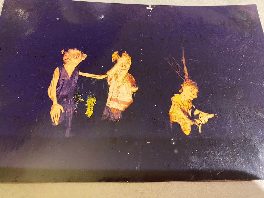 large puppets of exaggerated human faces and forms lit up in the night sky