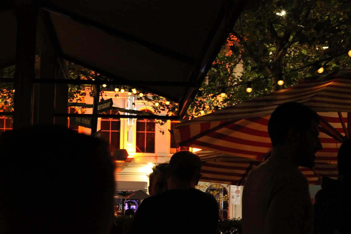 silhouette people drinking under fairy lights