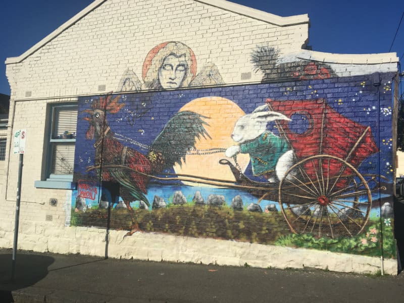 street art showing alice's rabbit driving a coach, pulled by a rooster