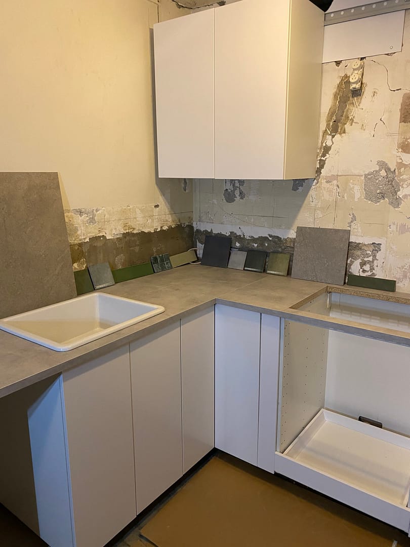 tile samples next to concrete walls and white cabinetry in new kitchen